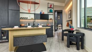 A modern kitchen and dining area with dark cabinets, a wooden island, a black dining set by a window, and decorative red lighting accents.